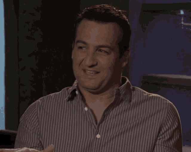 a man wearing a striped shirt is smiling and looking at the camera