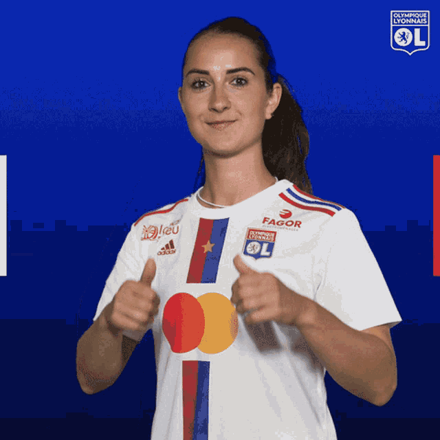 a woman wearing a white shirt that says olympique lyonnais giving a thumbs up