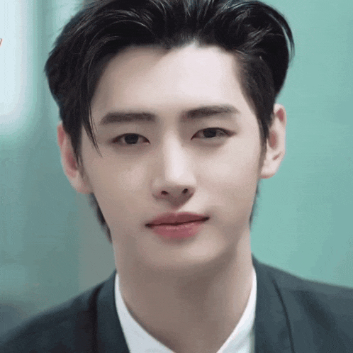a close up of a young man 's face wearing a suit and a white shirt .