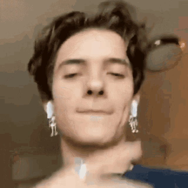 a close up of a man wearing ear buds and earrings .