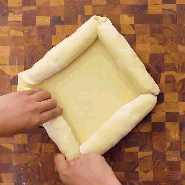 a person folds a piece of dough into a square