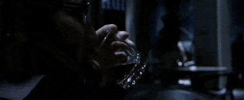 a man with a beard is drinking water from a bottle in a dark room .