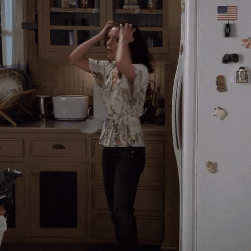 a woman stands in front of a refrigerator with an american flag magnet