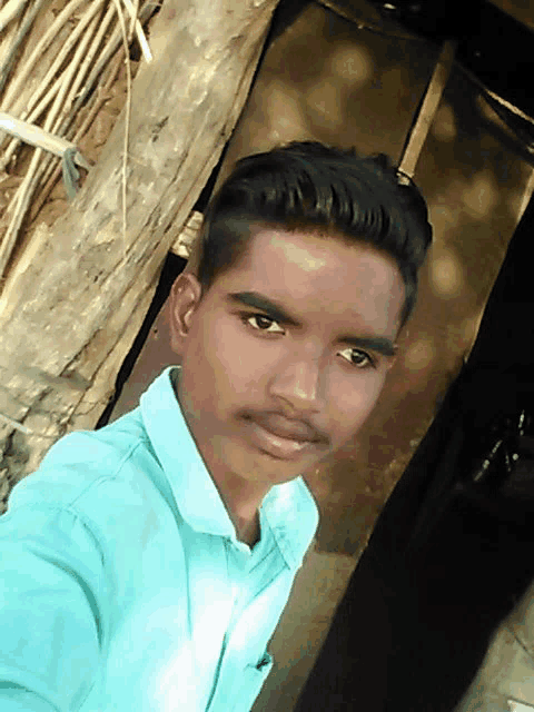 a young man in a blue shirt is standing in front of a wooden wall