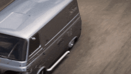 a gray van is driving down a road with a blurred background
