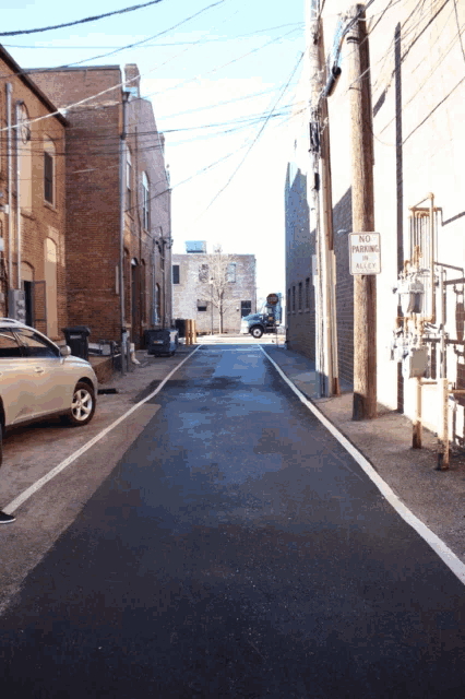 an alleyway with a no parking sign on a telephone pole