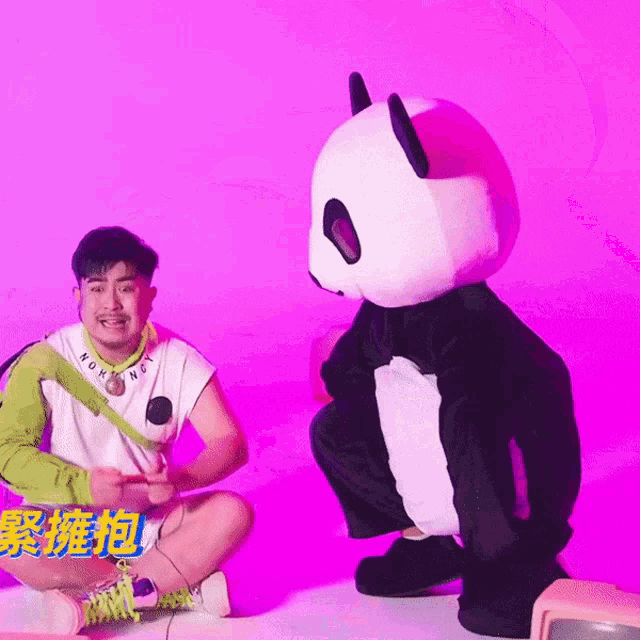 a man kneeling next to a stuffed panda bear wearing a white shirt that says morning on it