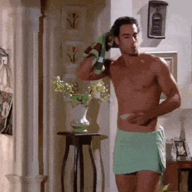 a shirtless man wrapped in a towel is standing in a hallway