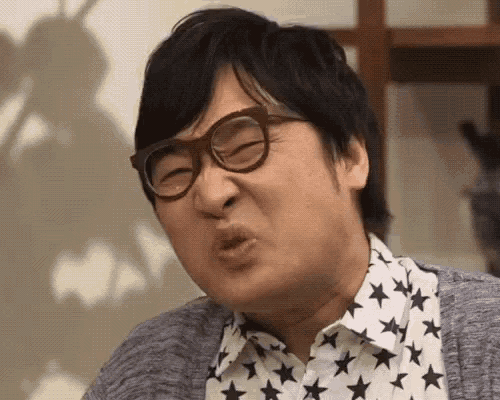 a man wearing glasses and a star print shirt is making a face .