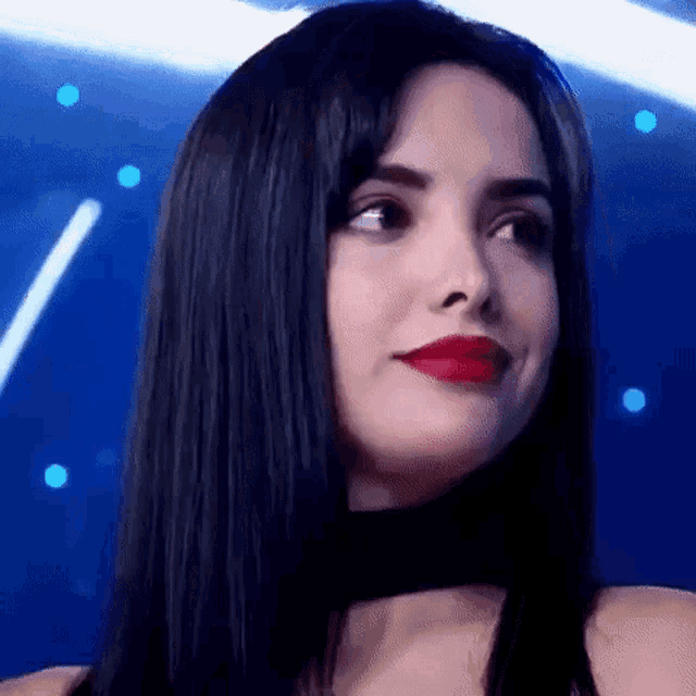 a close up of a woman with long black hair and red lipstick on a stage .