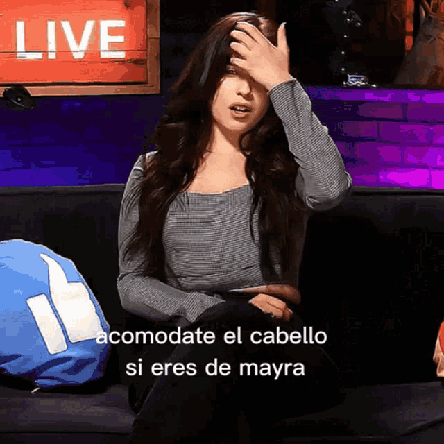 a woman sitting on a couch with a sign that says live behind her