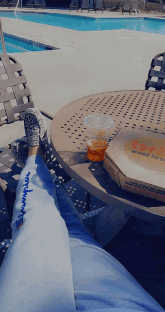 a box of pizza sits on a table next to a person