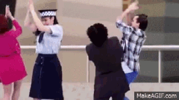 a group of people are dancing on a balcony and one of them is wearing a police uniform .