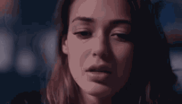 a close up of a woman 's face in a dark room with a blue background .