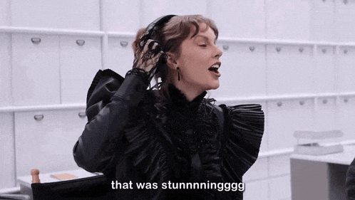 a woman in a black dress is sitting in a chair and says that was stunningggg .
