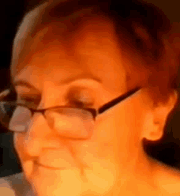 a close up of a woman 's face wearing glasses and smiling .