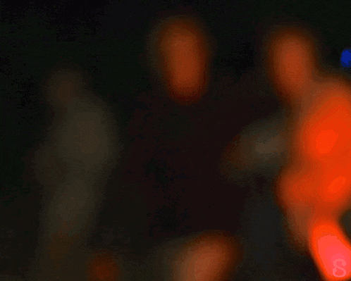 a blurry picture of a group of people in a dark room with the letter s in the corner