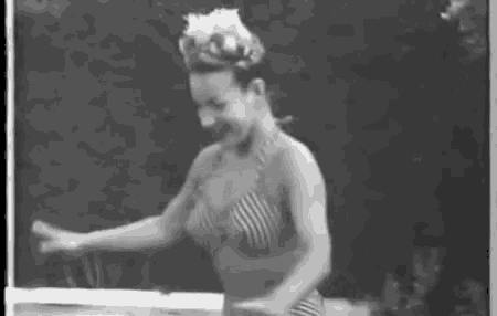 a black and white photo of a woman in a bikini dancing .