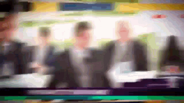 a blurry picture of a group of people standing in front of a sign that says ' a ' on it