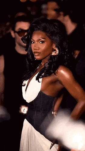 a woman in a black and white dress is standing in front of a crowd