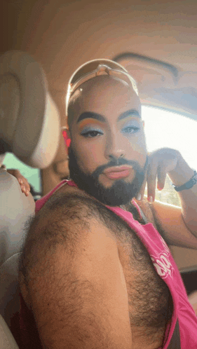 a man with a beard is wearing makeup and a pink tank top