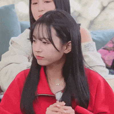 a girl wearing a red jacket and a necklace with a star on it is sitting on a couch