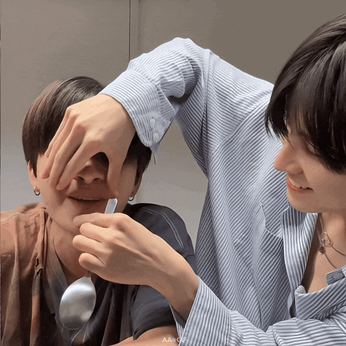 a person holding a spoon in front of another person 's face with the letters aa on the bottom right