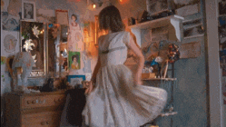 a woman in a white dress is standing in a room with a dresser .