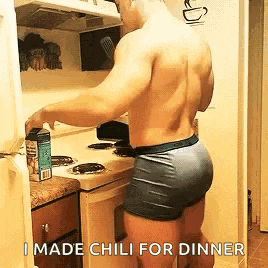 a shirtless man in underwear is standing in a kitchen preparing food .
