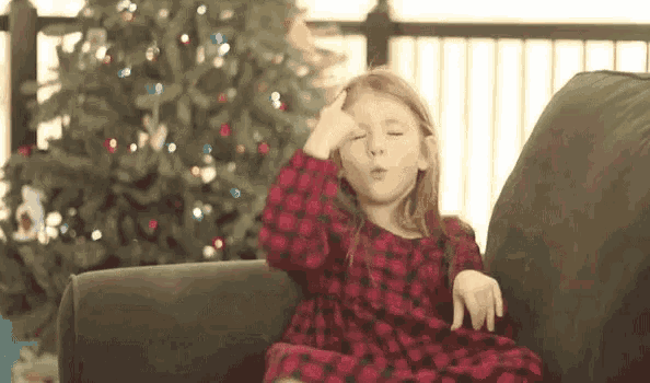 a little girl sitting on a couch with her eyes closed