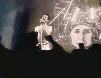 a man singing into a microphone with a shadow of a woman behind him