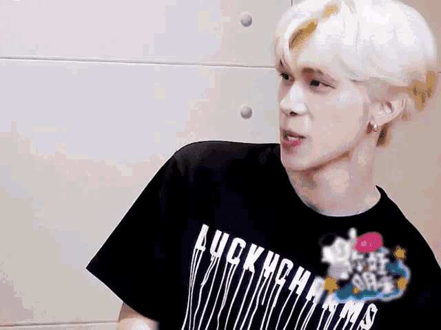 a young man with blonde hair is wearing a black t-shirt that says auckland on it .