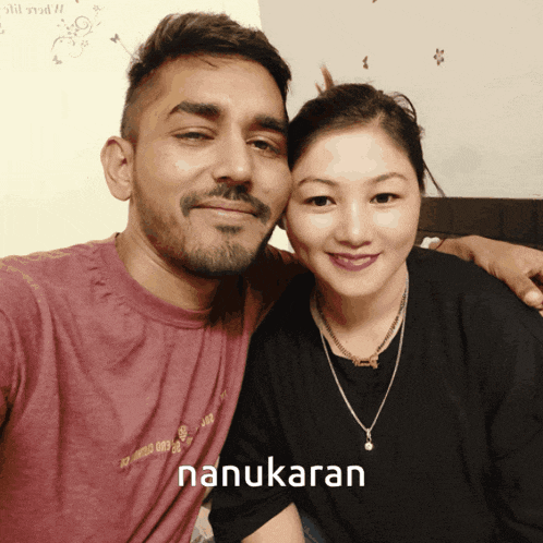 a man and a woman are posing for a picture and the woman is wearing a necklace that says nanukaran