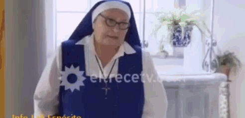 an elderly nun wearing glasses and a blue robe is standing in front of a sink .