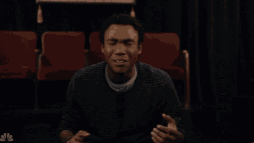 a man is singing in front of red seats with a nbc logo in the corner