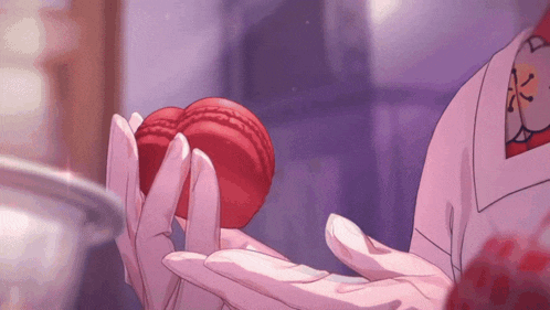 a person is holding a red macaron in their hands
