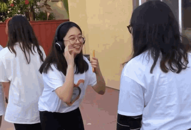 a girl wearing headphones is holding a stick and smiling