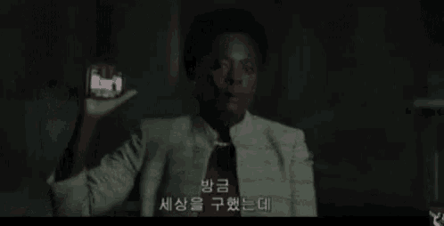 a man in a suit is holding a cell phone in his hand in a dark room
