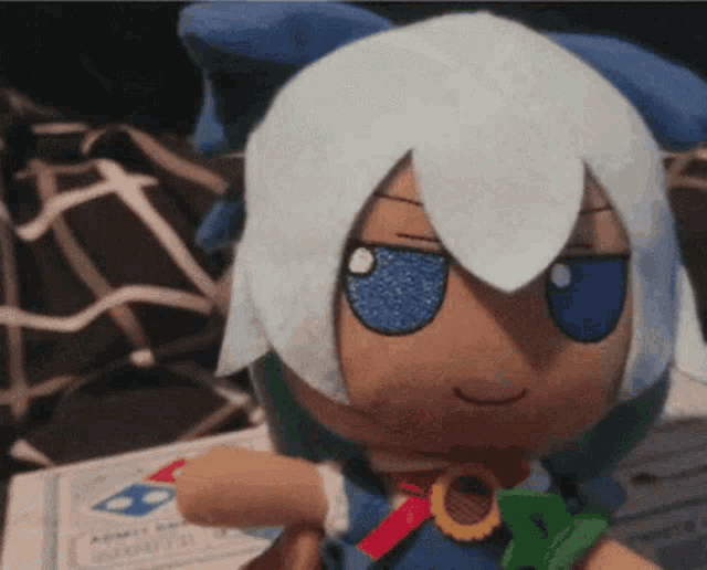 a stuffed doll with white hair and blue eyes is sitting on a piece of paper that says ' admit one ' on it .