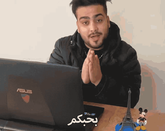 a man sitting in front of a laptop that says asus on it