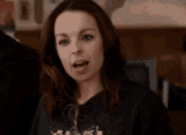 a woman in a black shirt is holding a pair of glasses and making a funny face .