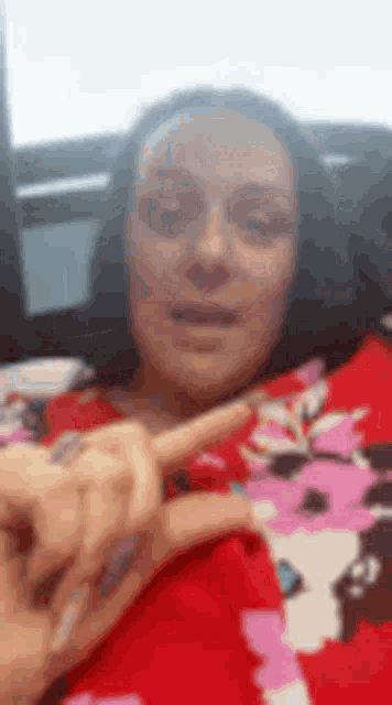 a woman in a red shirt is making a peace sign .