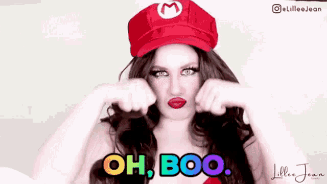 a woman is wearing a mario hat and making a funny face while saying oh boo .