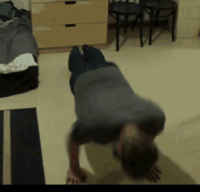 a man in a grey shirt is doing push ups