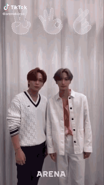 two young men are standing next to each other in front of a sign that says tiktok