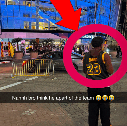 a man wearing a james 23 jersey stands in front of a large building