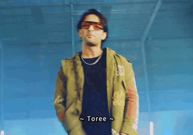 a man wearing sunglasses and a jacket with the word toree written on it