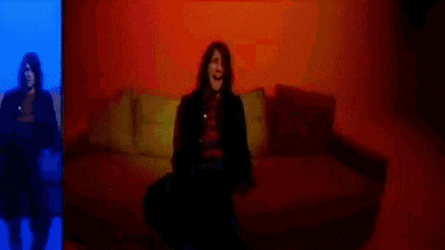 a blurry picture of a woman sitting on a couch in a dark room