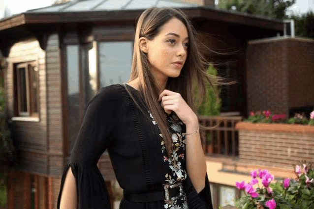 a woman in a black dress is standing in front of a building .
