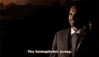 a man in a suit and tie is talking in a dark room .
